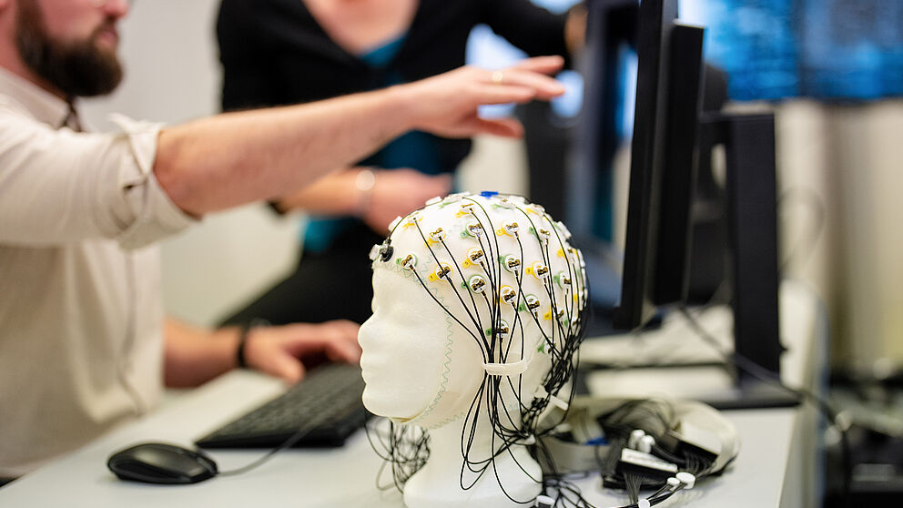Ein EEG System, im Hintergrund eine Person am Bildschirm